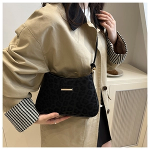 Détail du sac baguette léopard noir avec boucle dorée sur un trench-coat classique