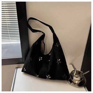 Detail of black suede tote bag with metallic silver floral studs and wide shoulder strap