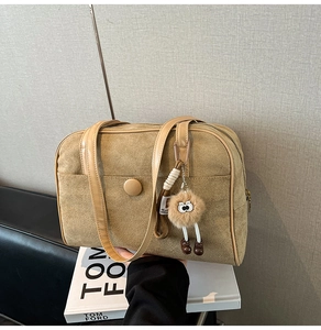 Detail of camel suede shoulder bag with retro circular buckle and fuzzy eye charm