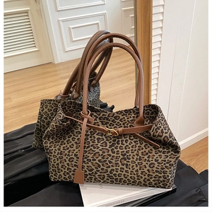 Detail of leopard print tote bag featuring brown leather handles and side buckle accents