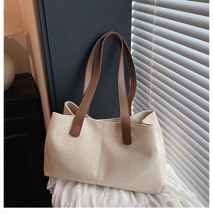 Detail of off-white woven tote bag with brown leather handles on lace background