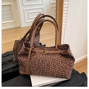 Detailed view of leopard print tote bag with brown leather handles and gold buckle