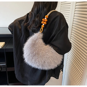 Détails de la texture du sac en peluche grise avec perles en bois orange sur la bandoulière