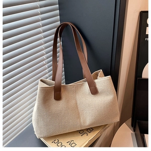 Detail of cream canvas tote bag with premium brown leather handle and fine stitching