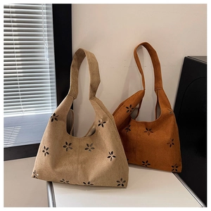 Detail of laser-cut flower patterns on suede tote bags in beige and brown colors