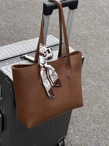 Brown large capacity tote bag with decorative scarf on a silver metal suitcase