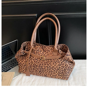 Close-up of leopard print tote bag with brown leather handles and gold metal buckle