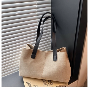 Detailed view of beige canvas tote bag with contrast black straps and visible side stitching