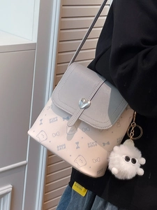Chic cream bucket bag with heart lock and cute cat prints shown on shoulder