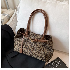 Close-up of leopard print tote bag with brown leather handles on a white sofa cushion