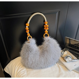 Détail du sac à main gris en peluche avec poignée tressée et perles décoratives