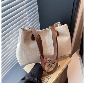 Detail of minimalist cream canvas tote bag with dark brown leather handles for commuting