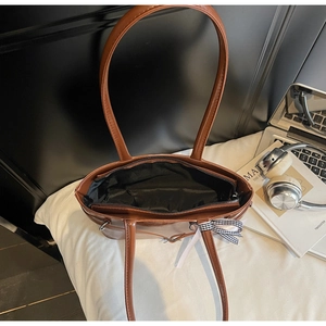 Dettaglio interno della borsa in pelle PU marrone con fodera nera e fiocco decorativo