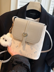 Chic two-tone bucket bag with heart buckle and plush charm on a textured leather finish