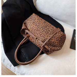 Detail of leopard print tote bag featuring brown leather straps and gold buckle accents