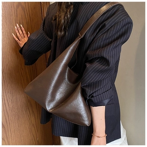 Detail of dark brown vintage faux leather hobo bag showing shoulder drape and smooth texture