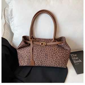Detail of leopard print suede tote bag with brown leather handles and gold buckles