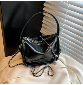 Détail d'un sac à main en similicuir noir avec bandoulière chaîne et logo de mode