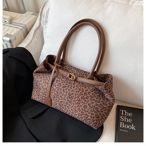 Detail of leopard print tote bag with brown leather straps and gold buckle on a sofa