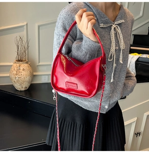 Détail d'un sac à main rouge brillant avec étiquette de mode et bandoulière chaîne