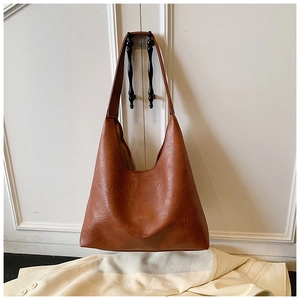 Detail of caramel leather tote bag showing grainy texture and fashion brand embossing