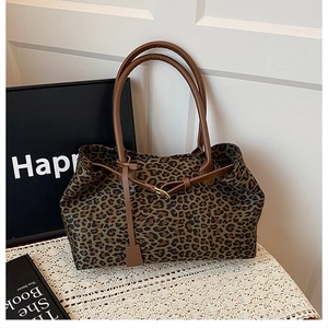 Detailed view of leopard print tote bag featuring brown faux leather handles and drawstrings