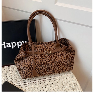 Close-up of leopard print tote bag featuring brown leather handles and gold metal buckle