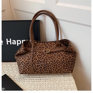 Detail of leopard print tote bag with brown handles and gold hardware on white lace