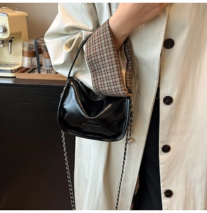 Détail du sac à main en cuir verni noir avec bandoulière chaîne et poignée chic