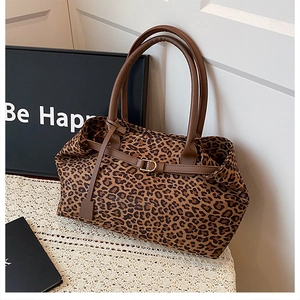 Detail of leopard print tote bag featuring brown faux leather strap and golden metal buckle