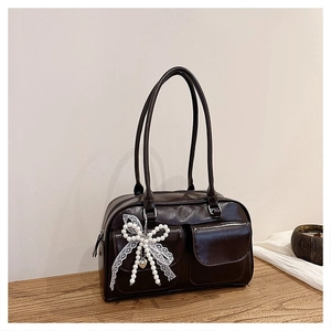 Close-up of retro brown tote bag featuring two front pockets and pearl bow charm