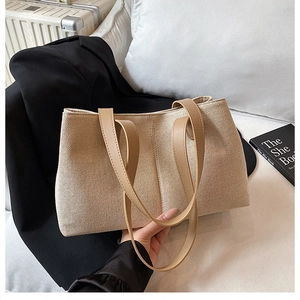 Close-up of beige canvas tote bag with brown leather straps and textured weave