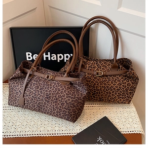 Detail of trendy leopard print tote bags with brown leather straps and gold metal buckles