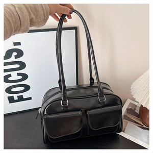 Close-up of glossy black leather tote bag featuring dual front pockets and silver zippers
