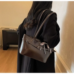 Dettaglio della borsa tote in pelle lucida marrone scuro con nastro decorativo a fiocco