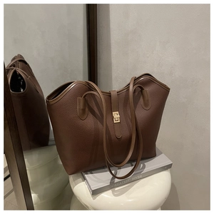 Close-up of coffee brown tote bag with lychee grain texture and gold metal twist lock