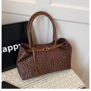 Detail of leopard print tote bag featuring brown leather straps and gold-tone hardware