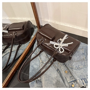 Close-up of dark coffee PU tote bag featuring pearl bow and silver heart pendant detail