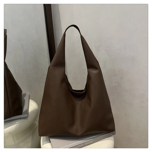 Macro detail of dark coffee tote bag showing premium litchi grain texture and soft leather
