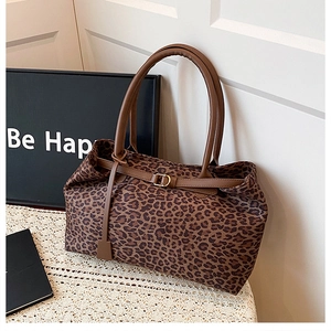 Close-up of leopard print tote bag with brown leather straps and gold metal buckle detail