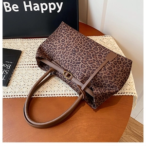 Macro detail of leopard print tote bag with brown leather handles and golden hardware
