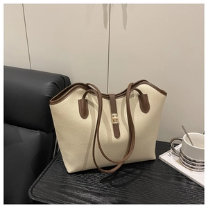 Detail of beige tote bag showing lychee grain leather texture and gold metal twist lock