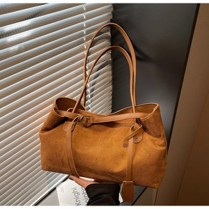 Detail shot of brown suede tote bag featuring slim handles and metallic buckle strap design