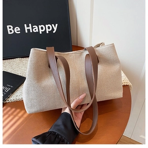 Detail of canvas tote bag with contrast leather handles and woven texture finish
