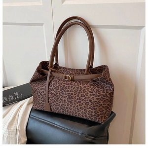 Detail of leopard print tote bag featuring brown faux leather straps and buckle closure