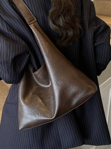 Retro dark brown large leather tote bag worn by model over a navy pinstripe blazer