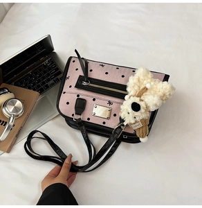 Detail of pink polka dot shoulder bag with cute teddy bear charm on white fabric
