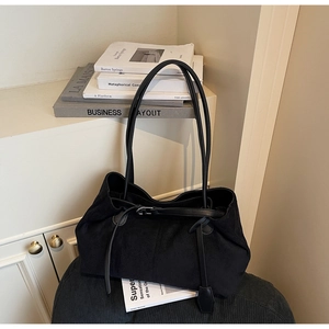 Detail of matte black tote bag with long shoulder strap and elegant buckle decoration