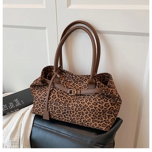 Macro detail of leopard print tote bag featuring brown leather handle and gold buckle