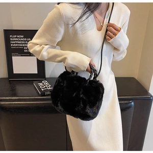 Detail of plush black faux fur handbag featuring a woven handle and adjustable strap